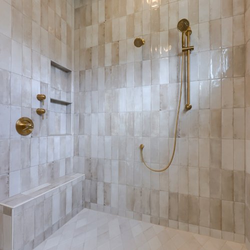 Glazed tile in a shower with gold hardware accents