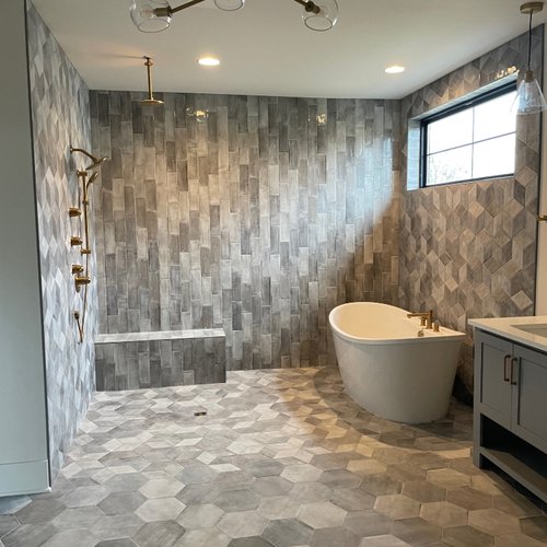 Grey tile floor and walls in a modern bathroom by Adair's Flooring