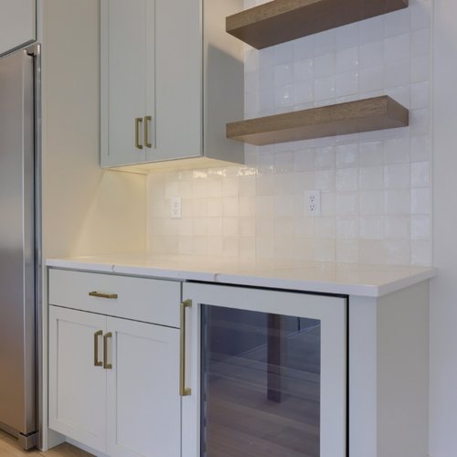 Kitchen with white cabinets and backsplash by Adair's Flooring